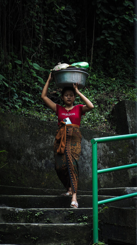 Girl water down steps at Tegenungan Waterfall with a bowl on her head