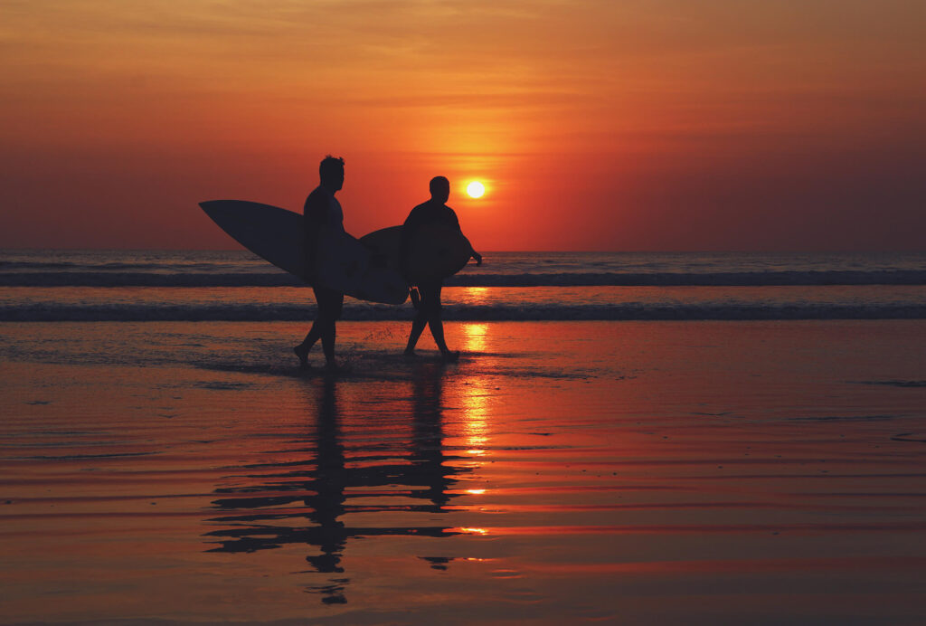 Silhouette of 2 surfers at sunset